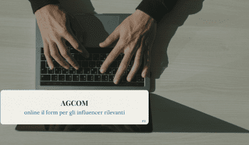 Mani su una tastiera di laptop, viste dall’alto, con un riquadro sovrapposto che riporta il titolo “AGCOM – online il form per gli influencer rilevanti”.